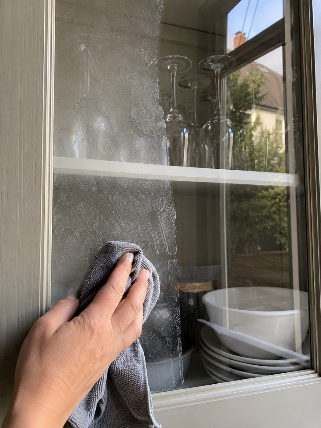 Smeared glass cabinet door being wiped clear.