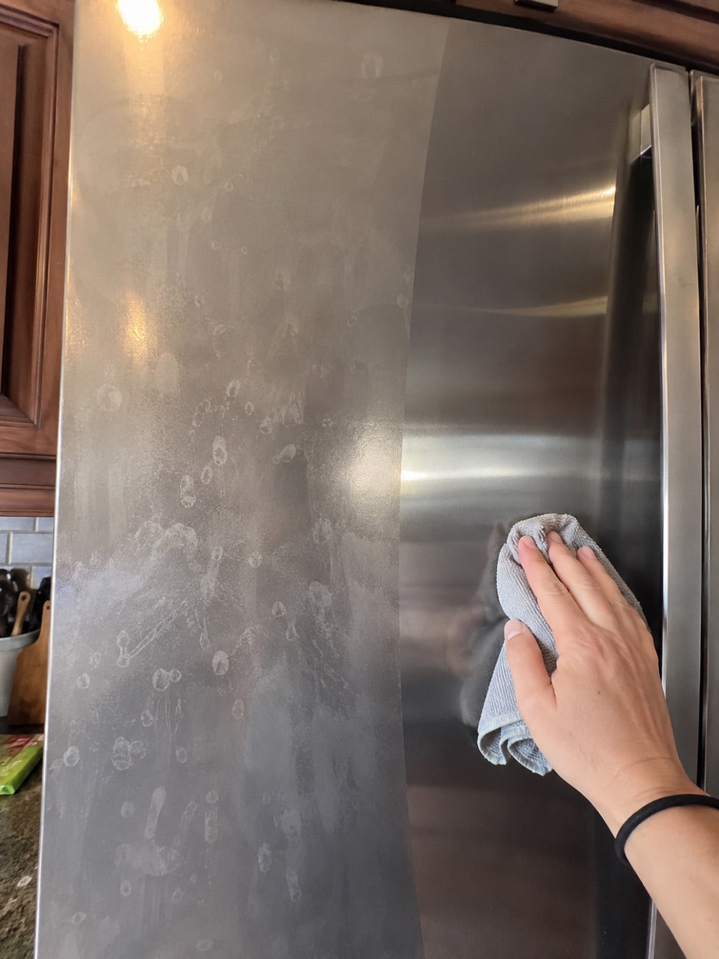 Stainless fridge door being wiped free of water spots.