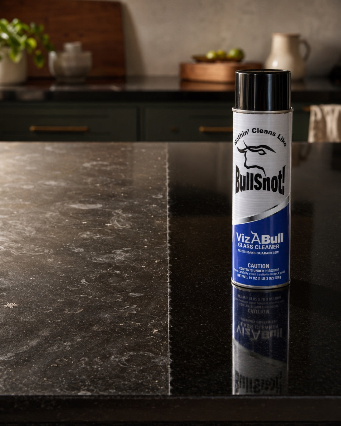 VizABull on a dark stone kitchen island, half of the surface still hazy with film and half wiped to a streak-free finish.