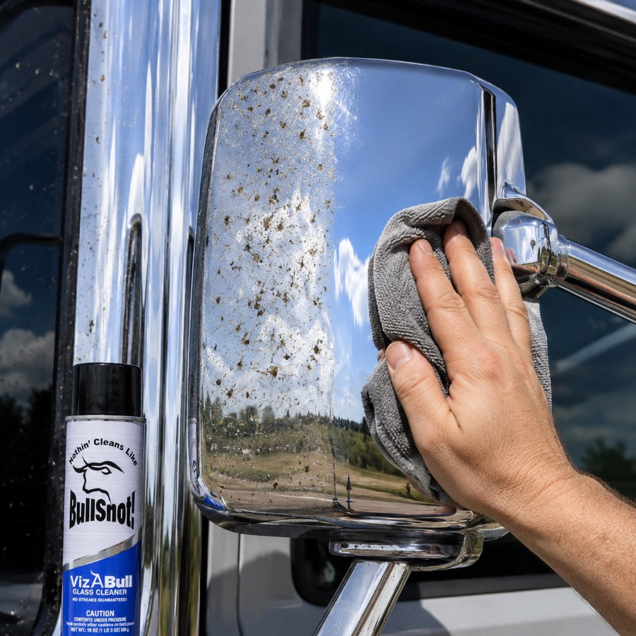A chrome wing mirror caked with bugs being wiped clean with VizABull